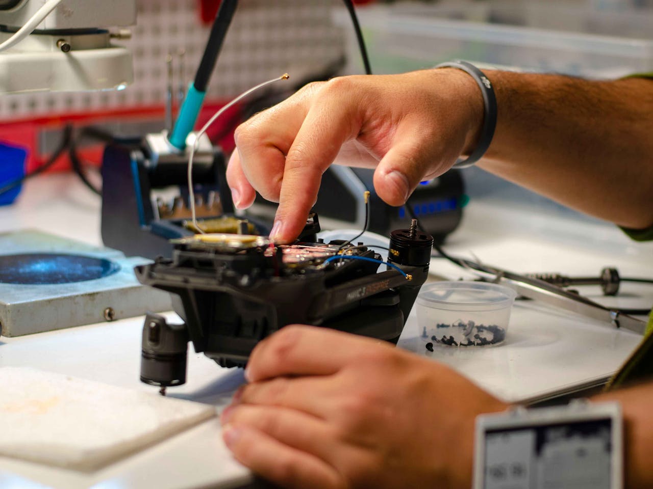 Hands of a technician performing drone repair on a workbench indoors.