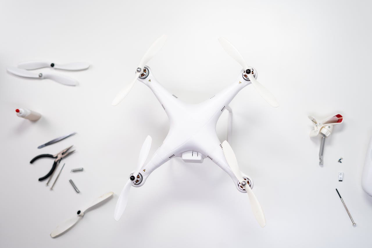 Overhead view of a drone being assembled with various tools on a white background.